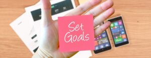 「Set Goals」と書かれた紙とスマホ、レジュメ