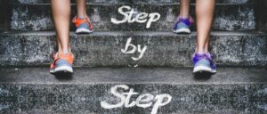 階段と人の足　「Step by Step」の文字