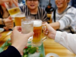 お酒が入ったグラスを合わせる人