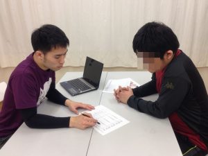 机を挟んでメモを見る二人