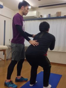 中腰になる人とその横で腰を支える人