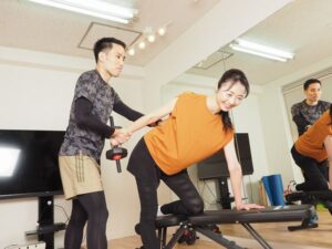 ダンベルを持つ女性と支える男性
