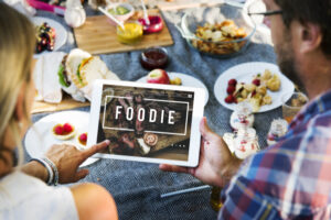 テーブルの上の食事とタブレットPCをのぞく人