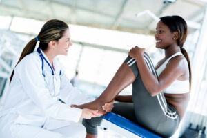黒人女性の足首を触る女医