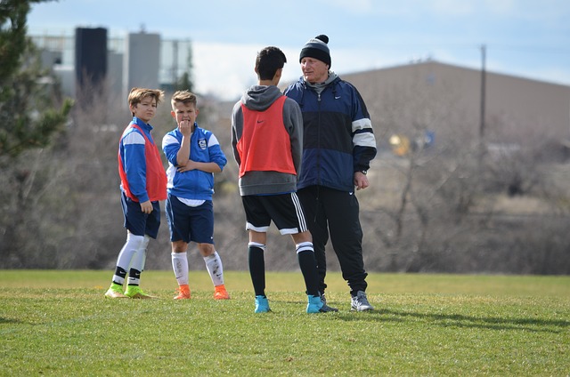 サッカーのコーチから指導を受ける子ども